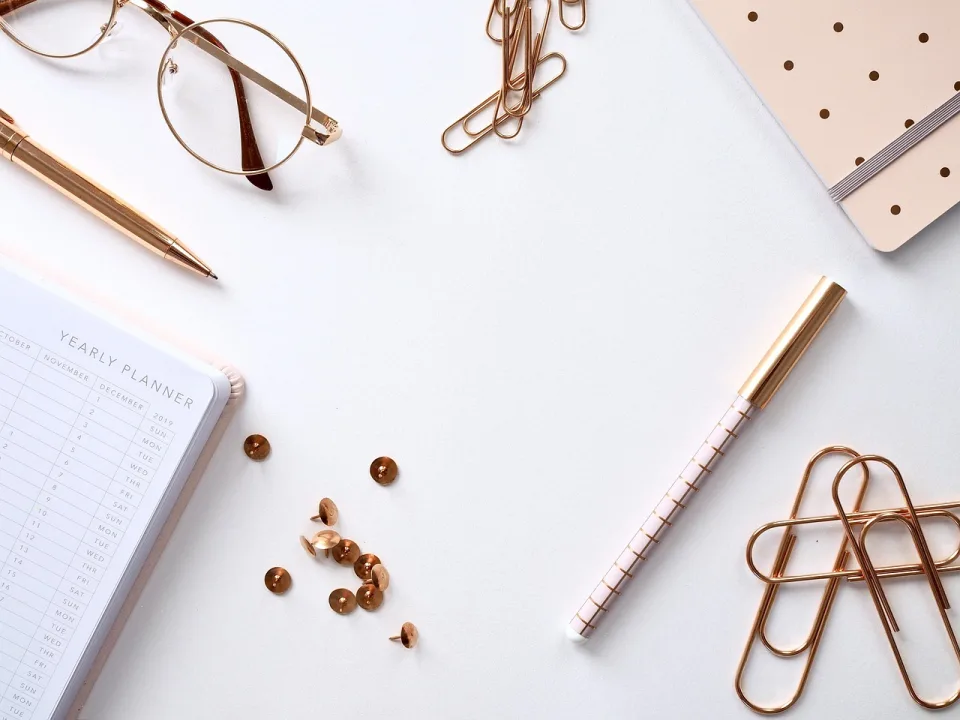 Agenda, gafas y útiles de escritura profesional sobre una mesa clara de despacho contable.