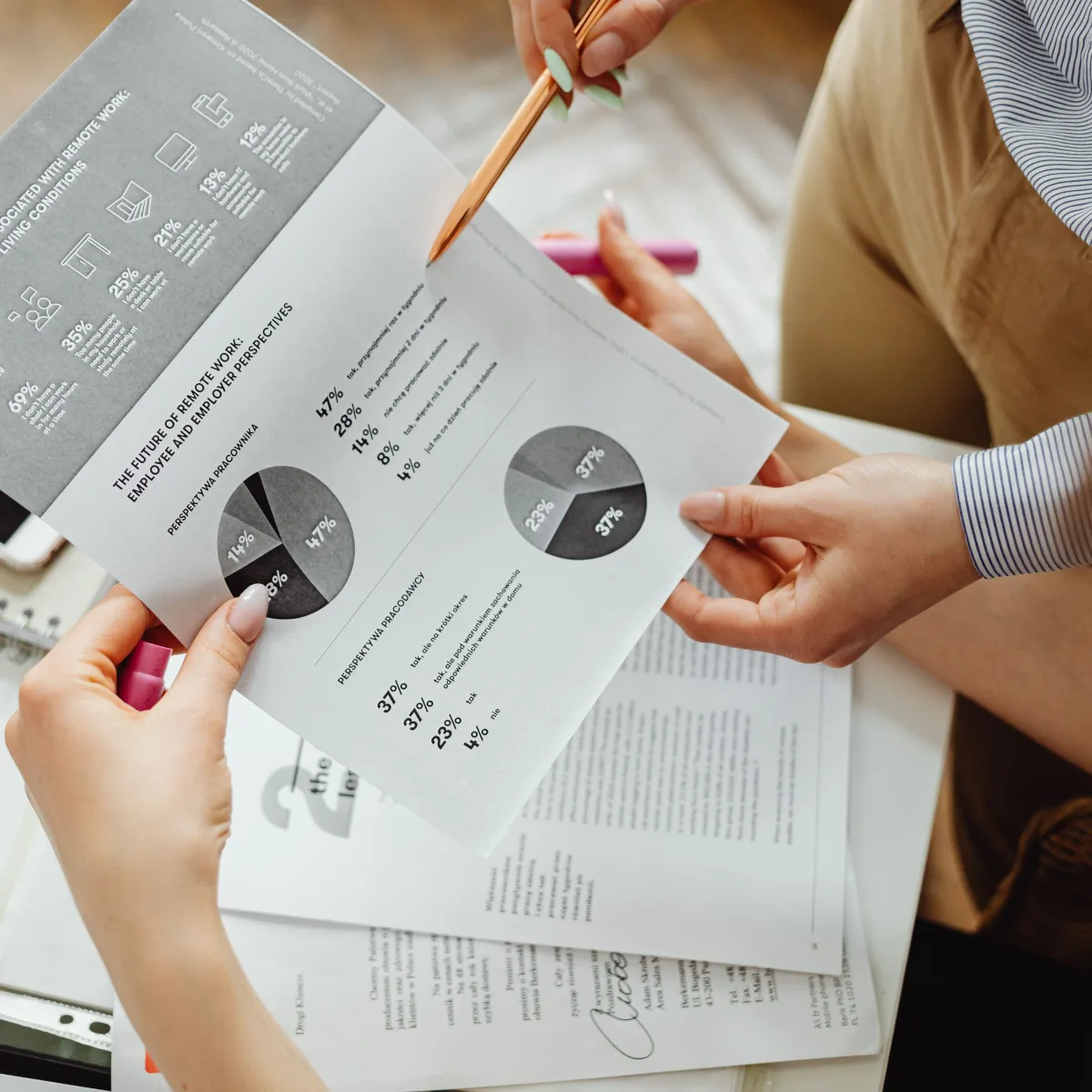 Manos revisando un informe con gráficos durante una sesión de análisis empresarial.